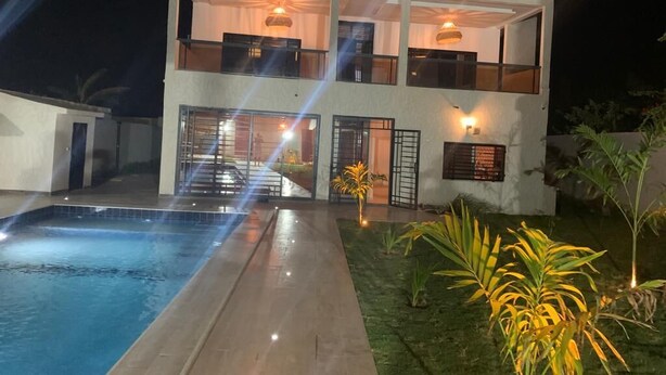 Un bâtiment à deux étages, avec une piscine en premier plan.