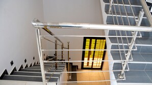 Un escalier avec des rampes en métal et une porte dotée d’une fenêtre teintée de jaune.