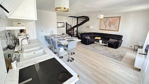 Una cucina moderna con zona pranzo, un divano in pelle nera e una scala che conduce a un piano superiore.