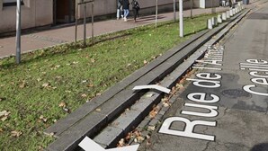 Un edificio a più piani con balconi, un marciapiede e una strada con una freccia direzionale.