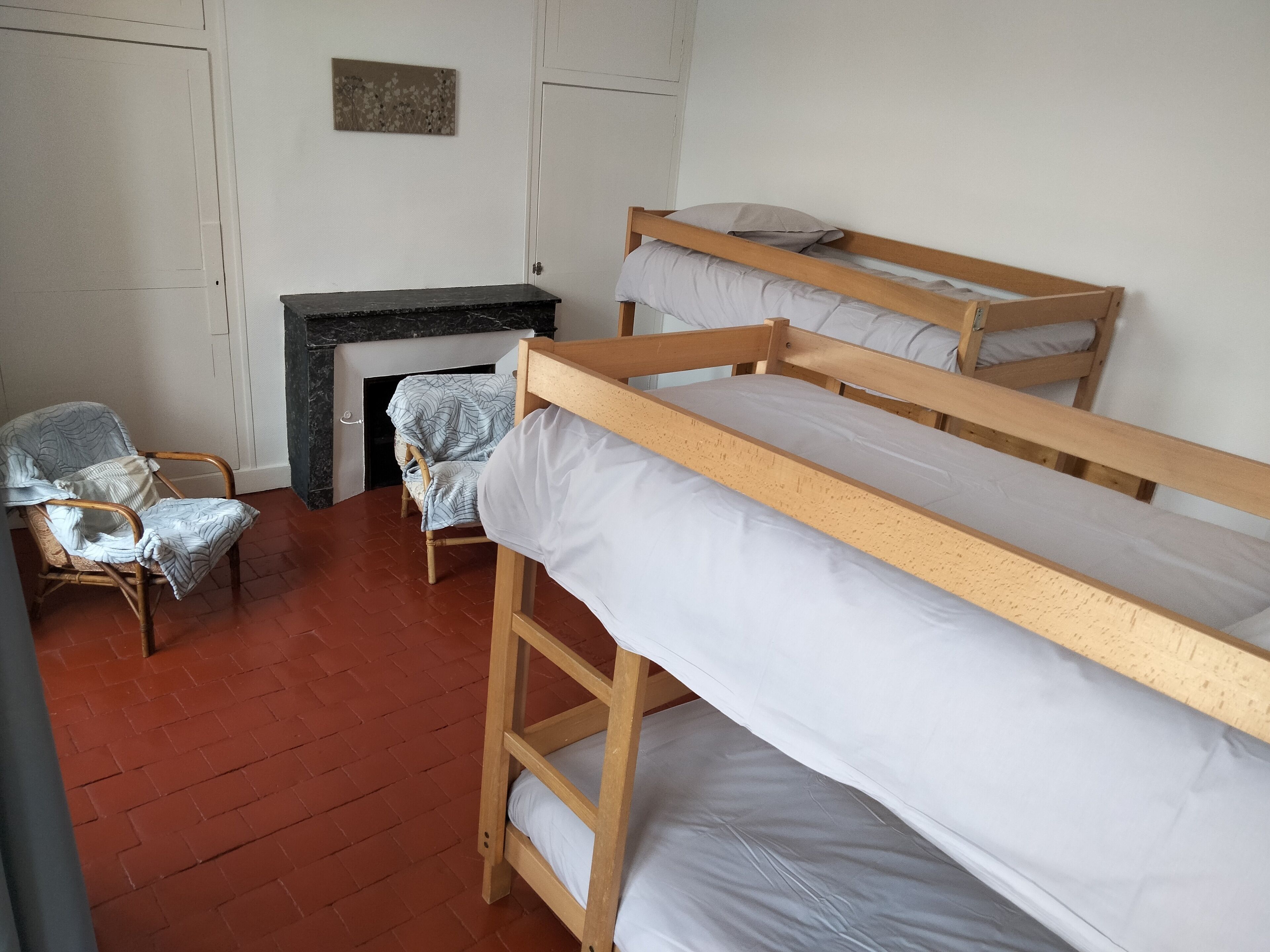 A room with bunk beds, a chair, and a fireplace.