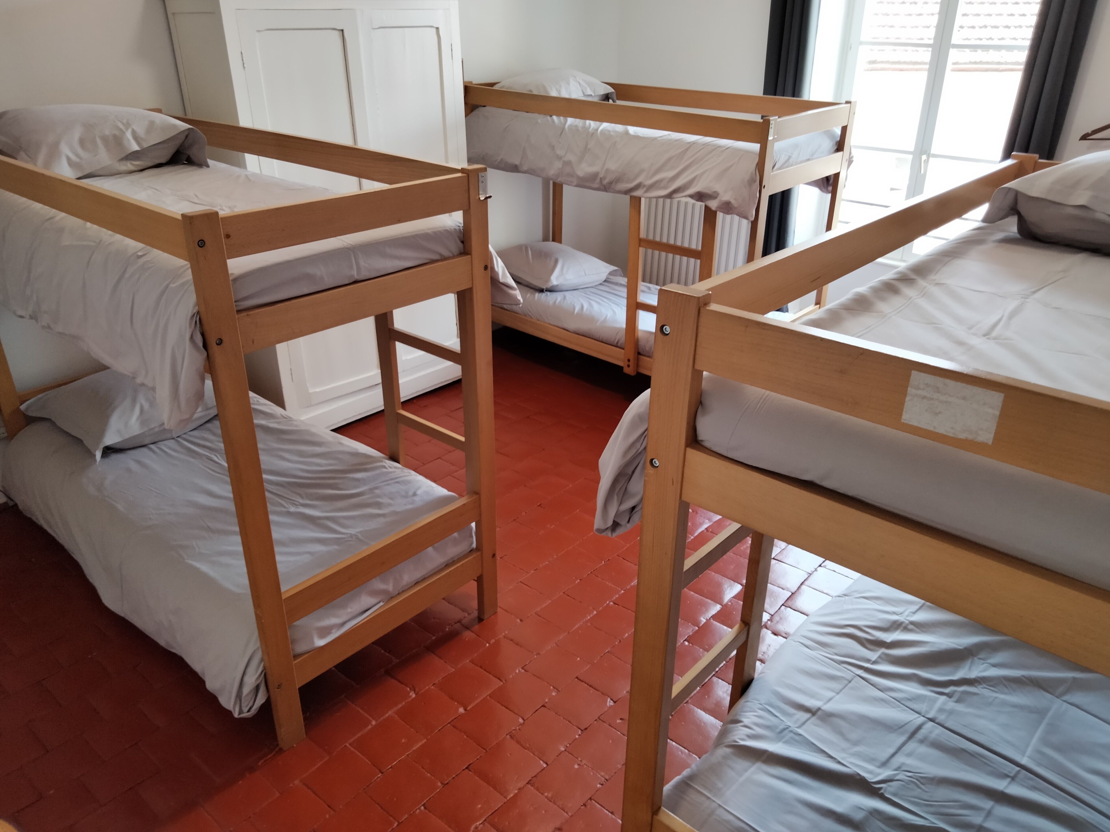 A dormitory room with bunk beds, a radiator, and a door.