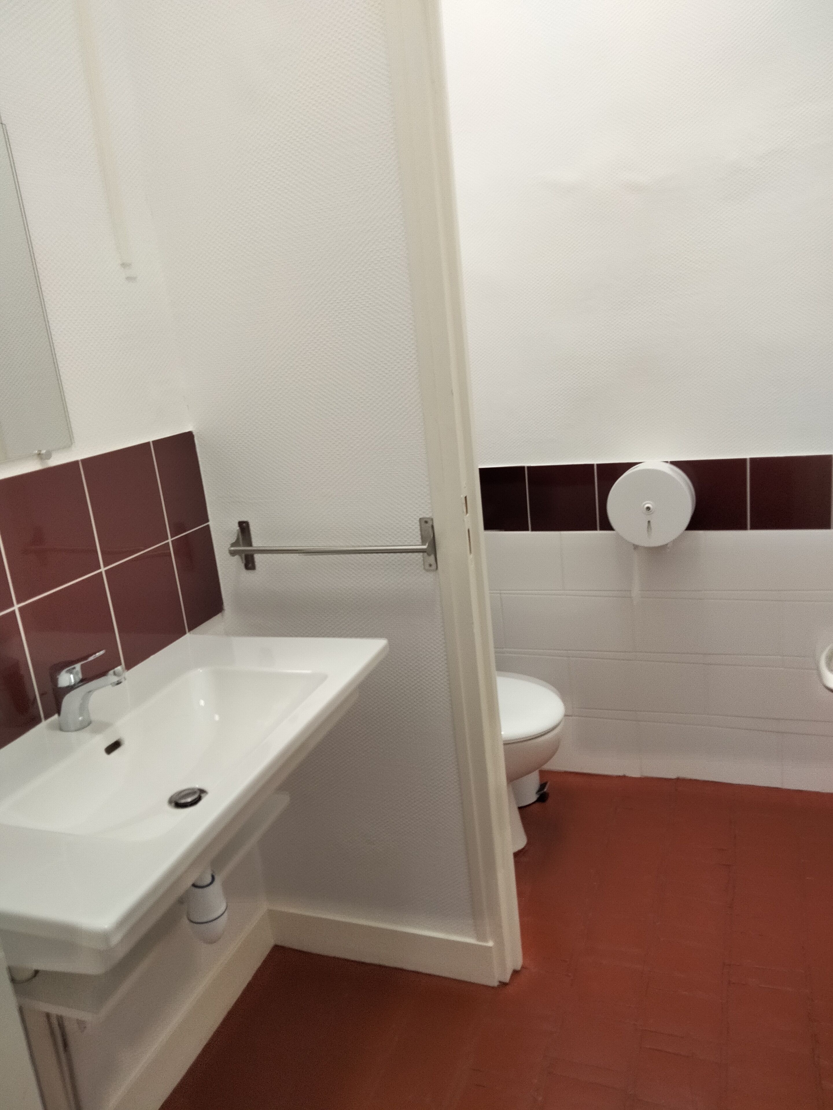 Ein Badezimmer mit weißem Waschbecken, Toilette und Duschbereich.