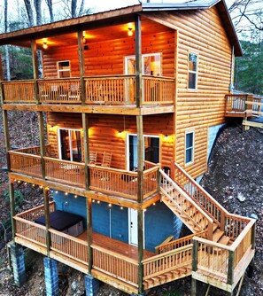 Une cabane en bois à plusieurs niveaux, dotée de balcons, d’escaliers et de guirlandes lumineuses.