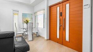 Un intérieur moderne avec un canapé en cuir noir, une table à manger avec des chaises et une porte orange.