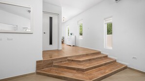 Un intérieur moderne avec un escalier, des murs blancs et une porte donnant sur une autre pièce.