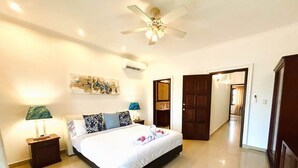 Un dormitorio amplio con una cama grande, un ventilador de techo y un equipo de aire acondicionado.