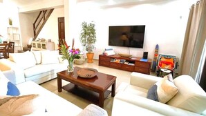 Una sala de estar con un sofá, una mesa de centro, un televisor y una escalera.