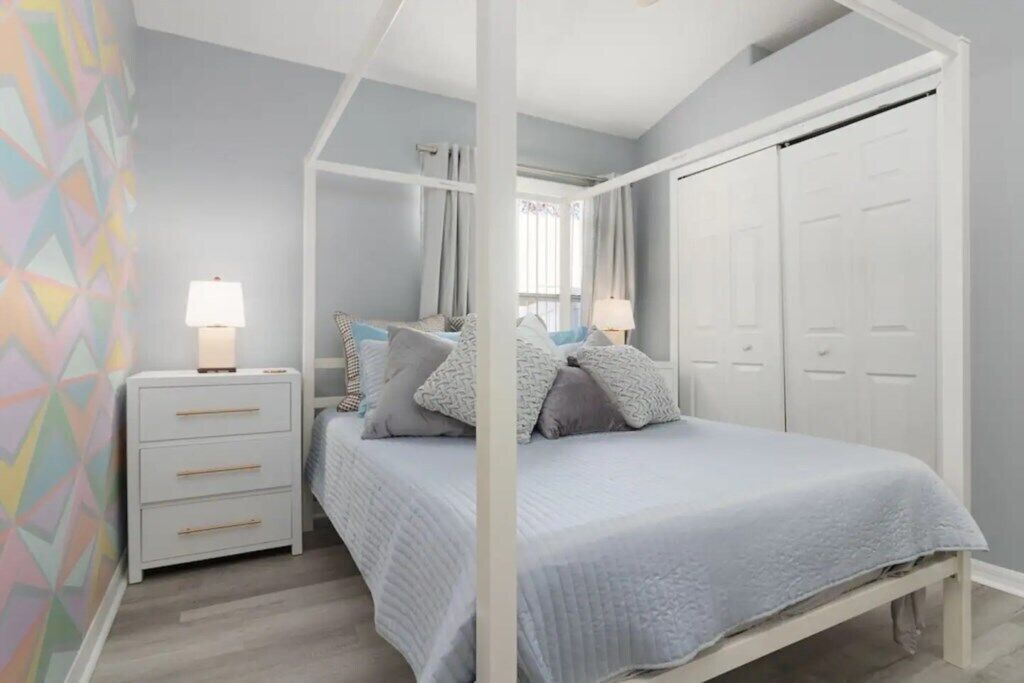 A bedroom with a canopy bed, white wardrobe, and bedside lamps.