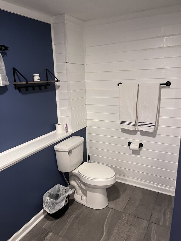 Een badkamer met een wit toilet, een blauwe wand en een vloer betegeld met witte tegels.