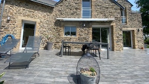 A stone house with a patio, outdoor seating, and a birdcage.