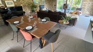 A dining area with a wooden table set for four, surrounded by stone walls and a piano.