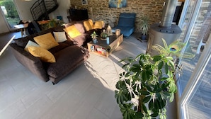 A cozy living room with a stone wall, a blue sofa, a brown sofa, and a coffee table.
