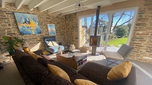 A cozy living room with a stone wall, a large sofa, a coffee table, and a fireplace.