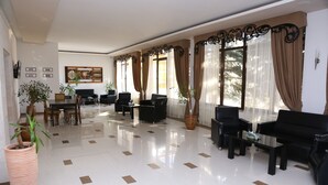 A spacious lobby with a polished floor, black sofas, and potted plants. - Ani Resort (Artavaz)