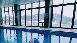An indoor swimming pool at Ani Resort with clear views of snow-covered mountains through large windows. - Ani Resort (Artavaz)