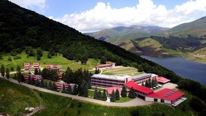 A hotel with multiple red-roofed buildings, a large central building, and a lake in the background. - Ani Resort (Artavaz)