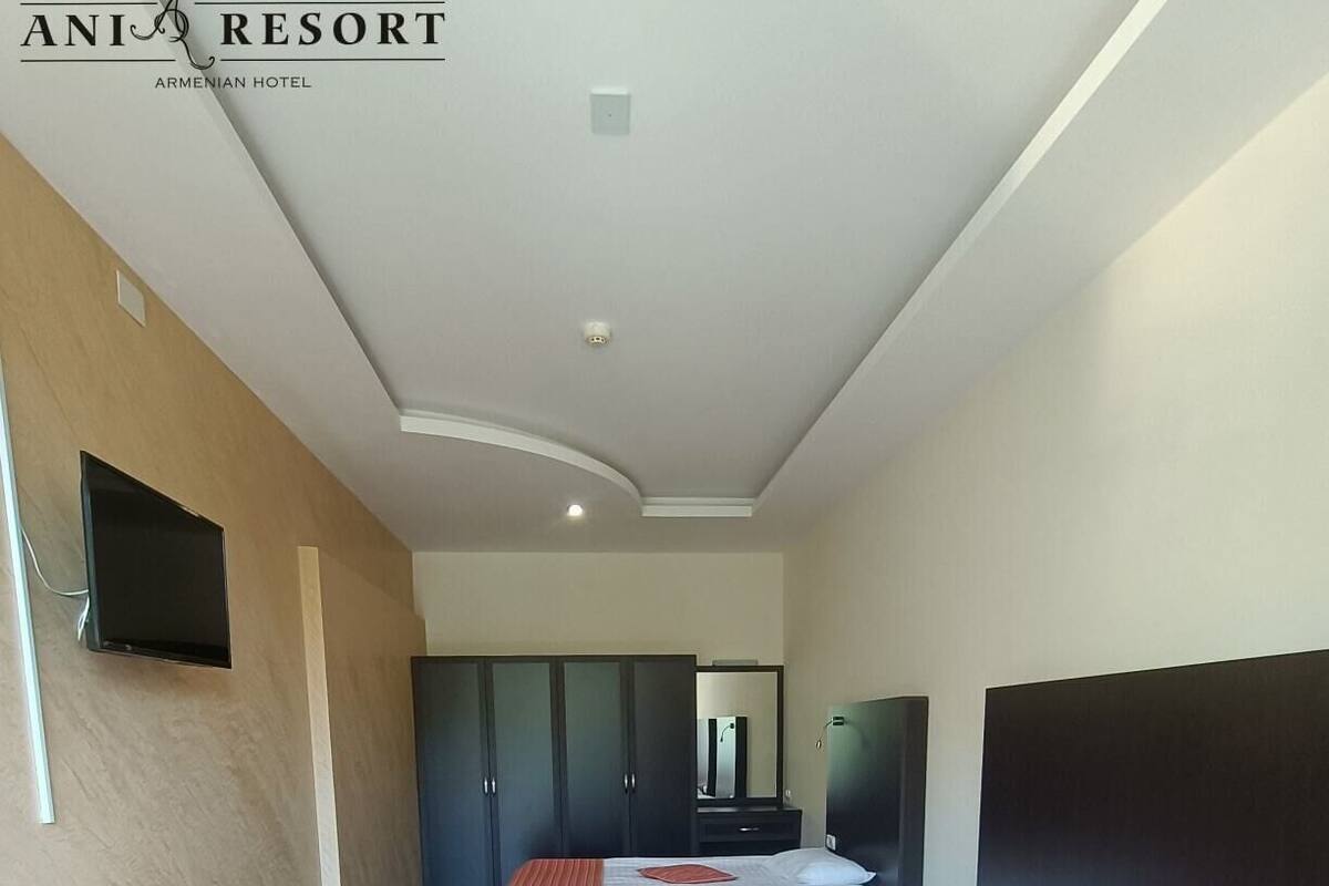 A hotel room with two beds, a TV, and a wardrobe.