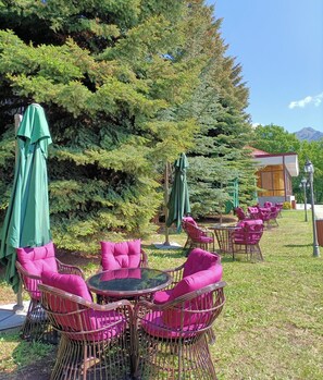 An outdoor seating area with wicker chairs and green umbrellas at Ani Resort Armenian Hotel.