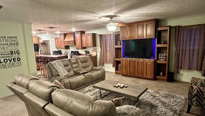 A living room with a sectional sofa, a coffee table, a TV, and wooden cabinets. - MC (Modern Country) LIVING (Elizabethtown)