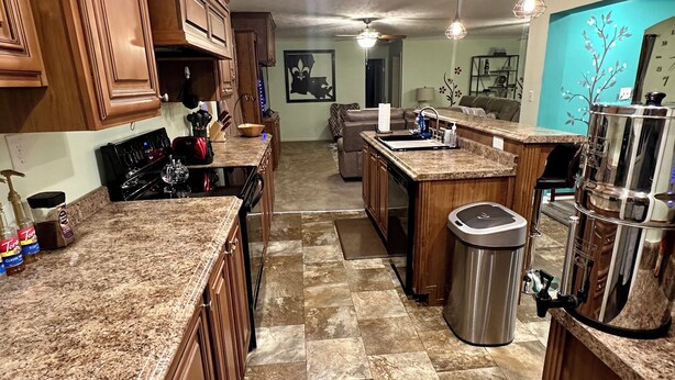A modern kitchen with granite countertops, wooden cabinets, and a stainless steel sink. - MC (Modern Country) LIVING (Elizabethtown)