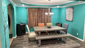 A dining area with teal walls, a chandelier, and a table with chairs. - MC (Modern Country) LIVING (Elizabethtown)