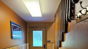 En hall med träpanel på väggarna, ett heltäckningsmatta på golvet, en dörr med ett fönster och en lampa i taket.