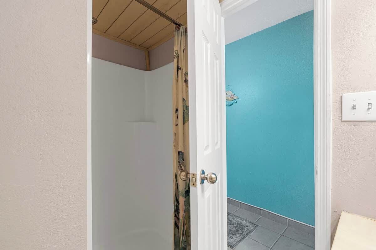 Una stanza con una porta bianca, un muro blu e un pavimento piastrellato.