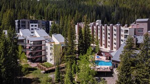 A modern hotel with multiple buildings, a swimming pool, and a forested mountain backdrop. - Mountain Escape and Adventure at Winter Park (Winter Park)