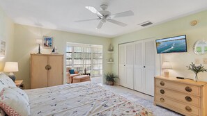 A bedroom with a bed, a dresser, a television, a ceiling fan, and a window with blinds.