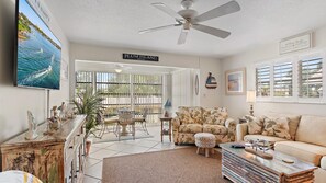 A living room with a large TV, a ceiling fan, and a sign reading "PLUM ISLAND".