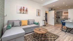 A modern living room with a grey sofa, a wooden coffee table, and a patterned rug. - The Cotswold Woodland by Fortuna Property Portfolio (Cheltenham)