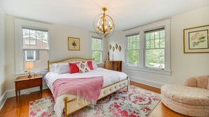 Un dormitorio con cama, candelabro, cómoda y silla.