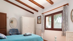 A bedroom with two beds, a wardrobe, a chair, and a window with curtains.