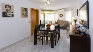 A dining area with a table and chairs, a coffee machine, and artwork on the walls. - FUENTE Beachfront Apartment (Salou)