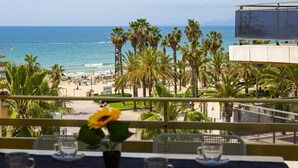 A balcony with a view of the beach, palm trees, and a clear sky. - FUENTE Beachfront Apartment (Salou)