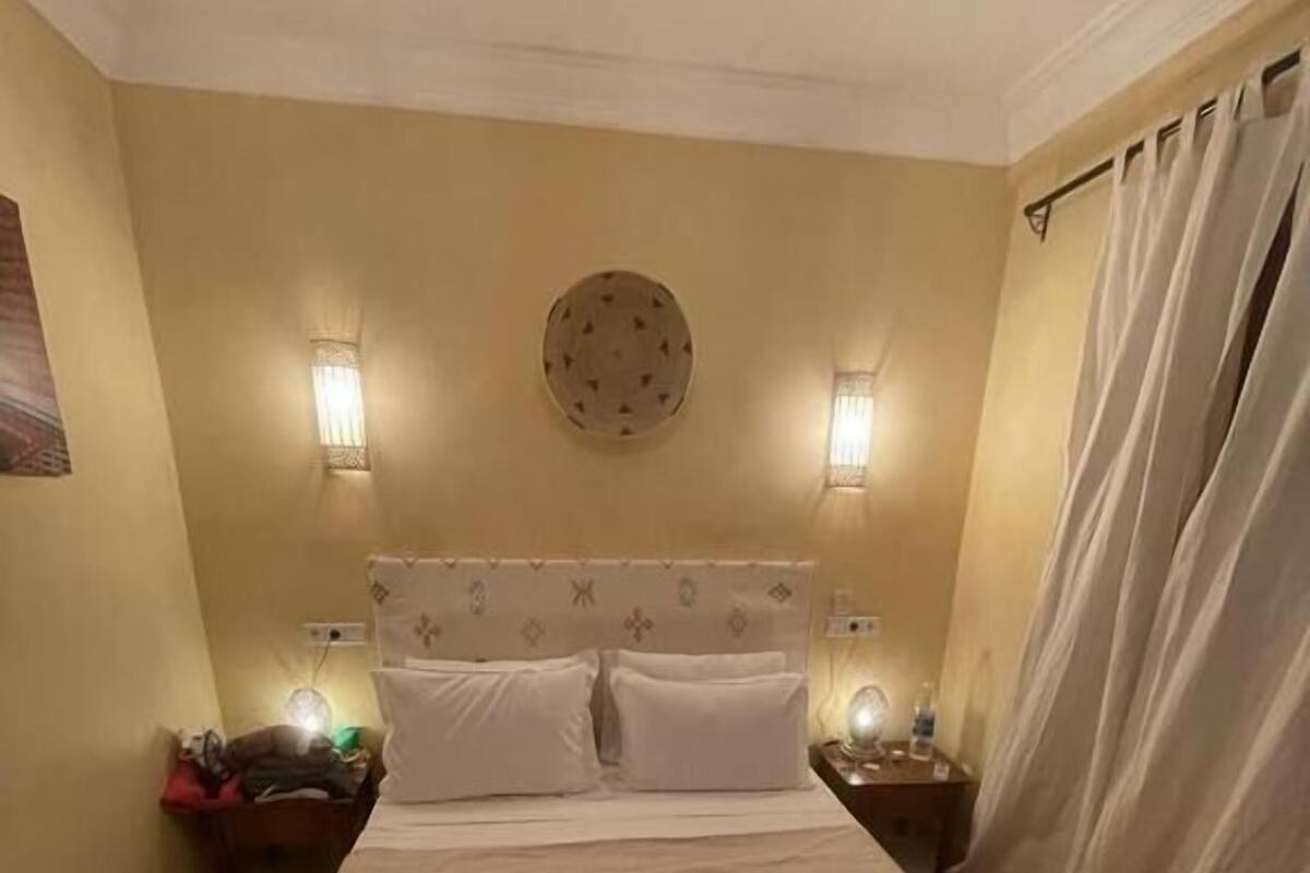 A hotel room with a large bed, two bedside tables, a round wall decoration, and a curtain.