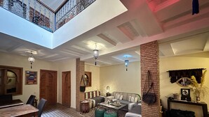 A spacious living area with a high ceiling, a dining table, a sofa, and a coffee table. - Riad Les Miroires (Marrakech)