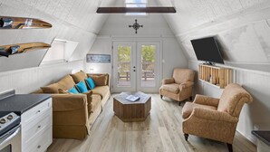 En hyggelig loftstue med stort vindue, pejs, fjernsyn og spiseplads.