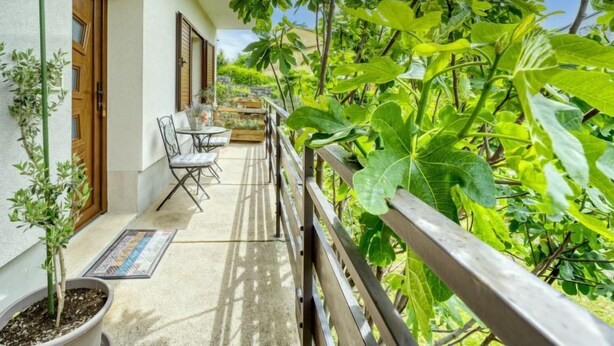 Ein Balkon mit Holzwerteln, einem kleinen Tisch und Stühlen sowie Topfpflanzen.