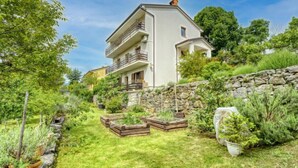 Ein mehrstöckiges Haus mit einer Steinmauer und einem Rasengarten.