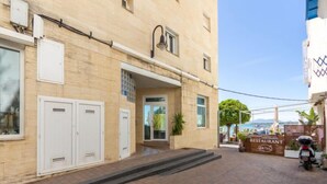 A building with a beige facade, a covered entrance, and a sign for a restaurant. - Apartment Narcis by Interhome (L'Ampolla)