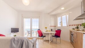A modern living room with a sofa, a TV, and a dining area with chairs and a table. - Apartment Narcis by Interhome (L'Ampolla)
