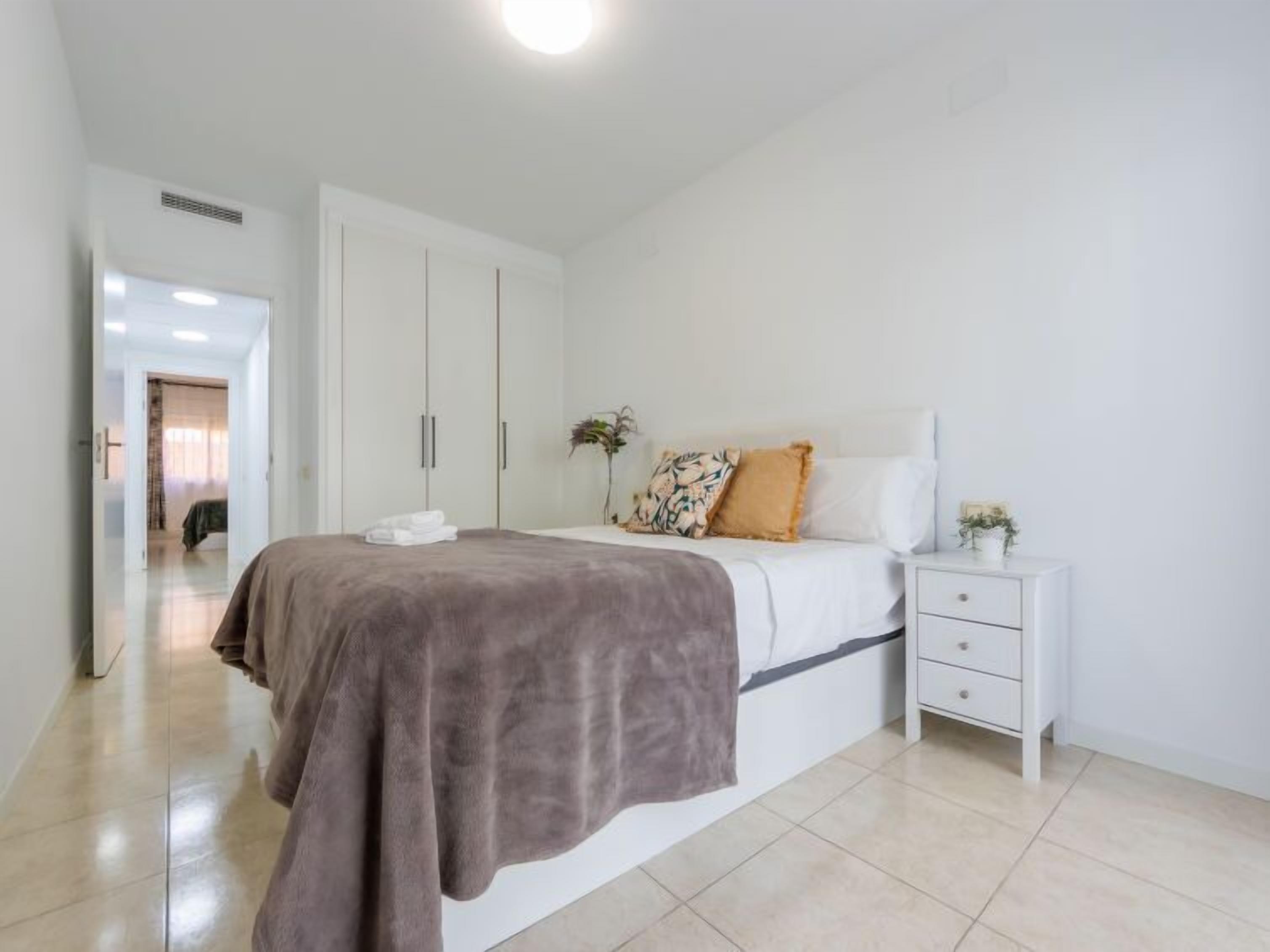 A bedroom with a bed, bedside table, and a wardrobe.