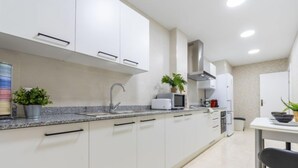 Una cocina moderna con armarios blancos, encimera de granito y electrodomésticos de acero inoxidable.