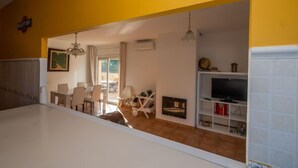 Un salon comprenant un coin repas, une cheminée et un téléviseur.
