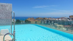 A rooftop infinity pool with clear blue water, a glass railing, and a view of the sea and cityscape. - Estepona Roof Top View 5 by Interhome (Estepona)