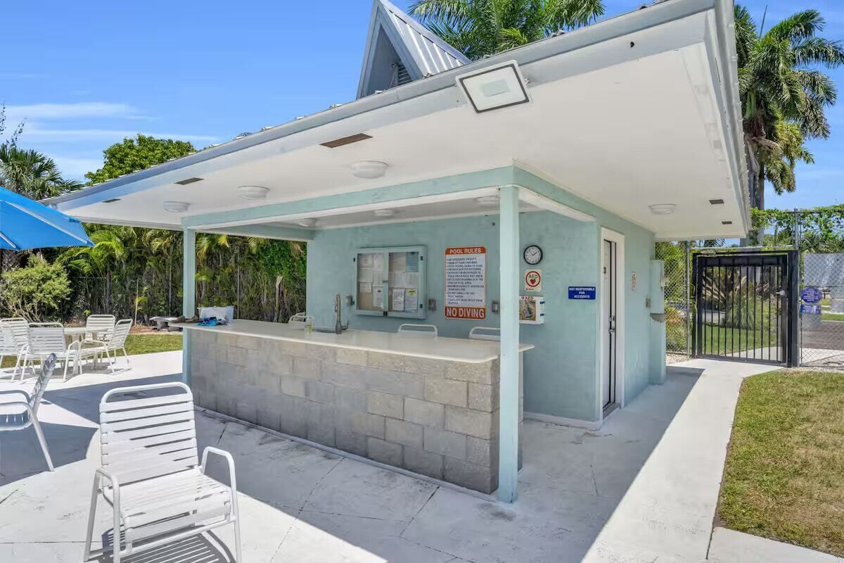 A pool area with a covered seating area, a reception desk, and a sign indicating no diving.
