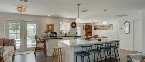A spacious kitchen with a large island, bar stools, and a dining area with a pool view.