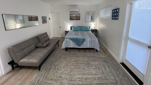 Un dormitorio con una cama, un sofá, una alfombra, un espejo y una puerta.